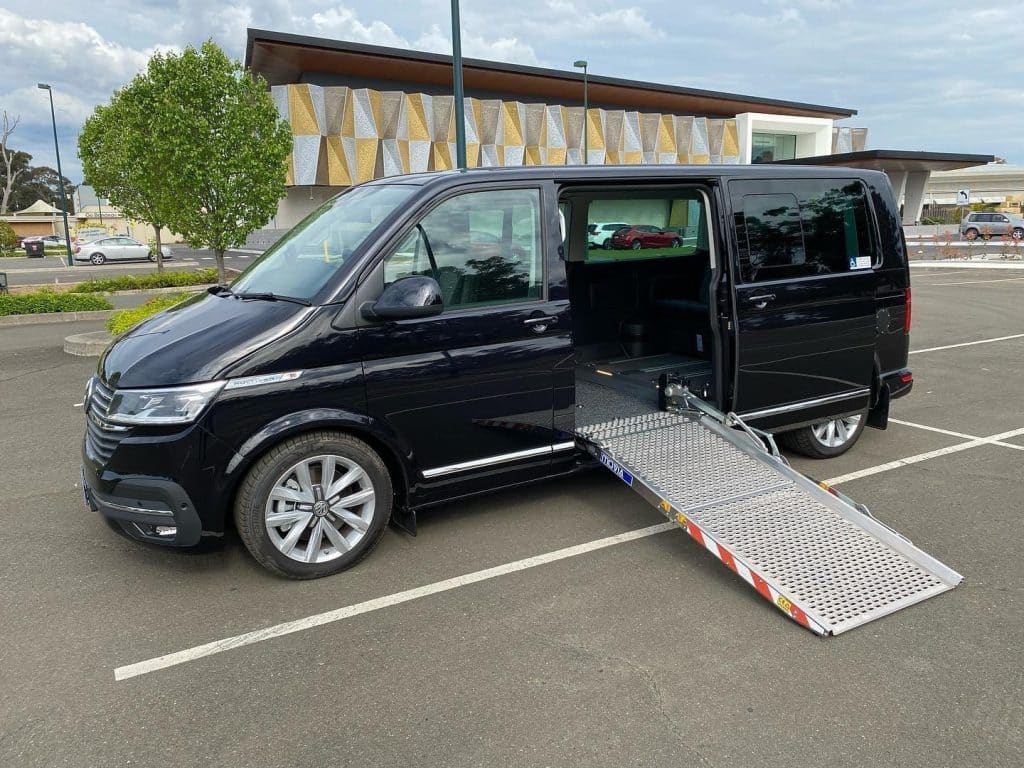 Side view of Black VW Transporter van with Movia ramp opened up on side sliding door.
